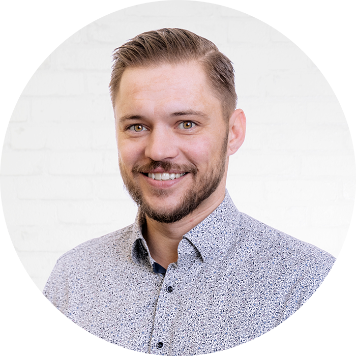 Porträt des IT-Consultants und Key Account Managers Stefan Milde vor einer neutralen Wand aus weißen Backsteinen.
