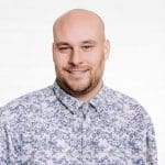 Porträt des Key Account Managers Matthias Arndt vor einer neutralen Wand aus weißen Backsteinen.