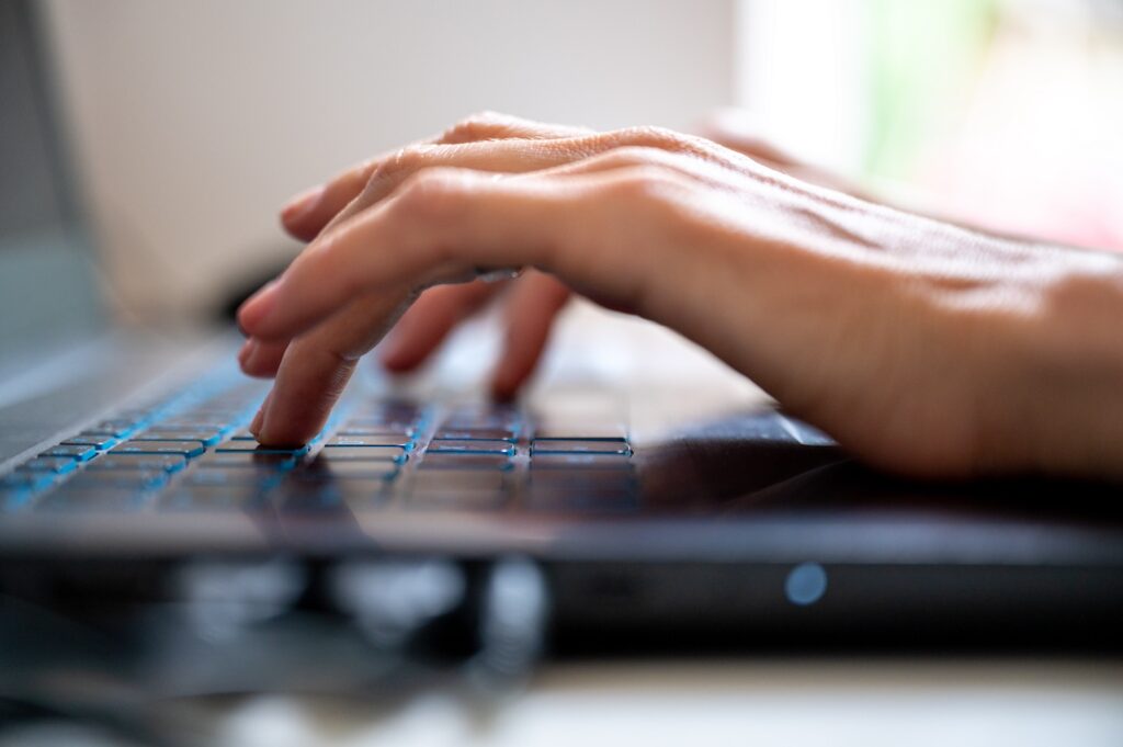 Low angle view of female fingers typing on laptop computer keyboard.