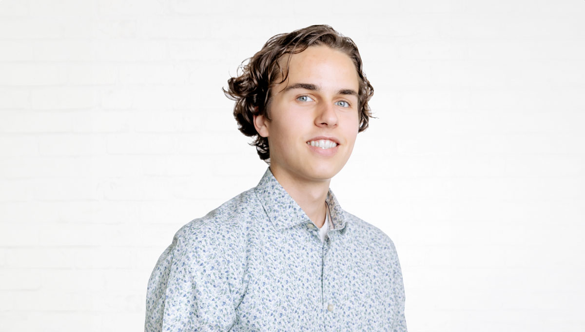 Porträt des Werkstudenten Nils Söder vor einer neutralen Wand aus weißen Backsteinen.