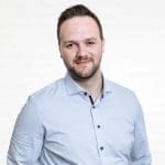 Porträt des IT-Consultants Manfred Schuster vor einer neutralen Wand aus weißen Backsteinen.