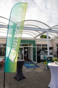 Eingangsbereich beim Kutzschbach Partnertag 2025 mit Kutzschbach-Werbefahne und offenem Eingang unter Glasüberdachung