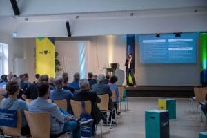 Mann hält Vortrag auf Bühne vor Publikum beim Kutzschbach Partnertag 2025, Präsentation mit Text auf Leinwand