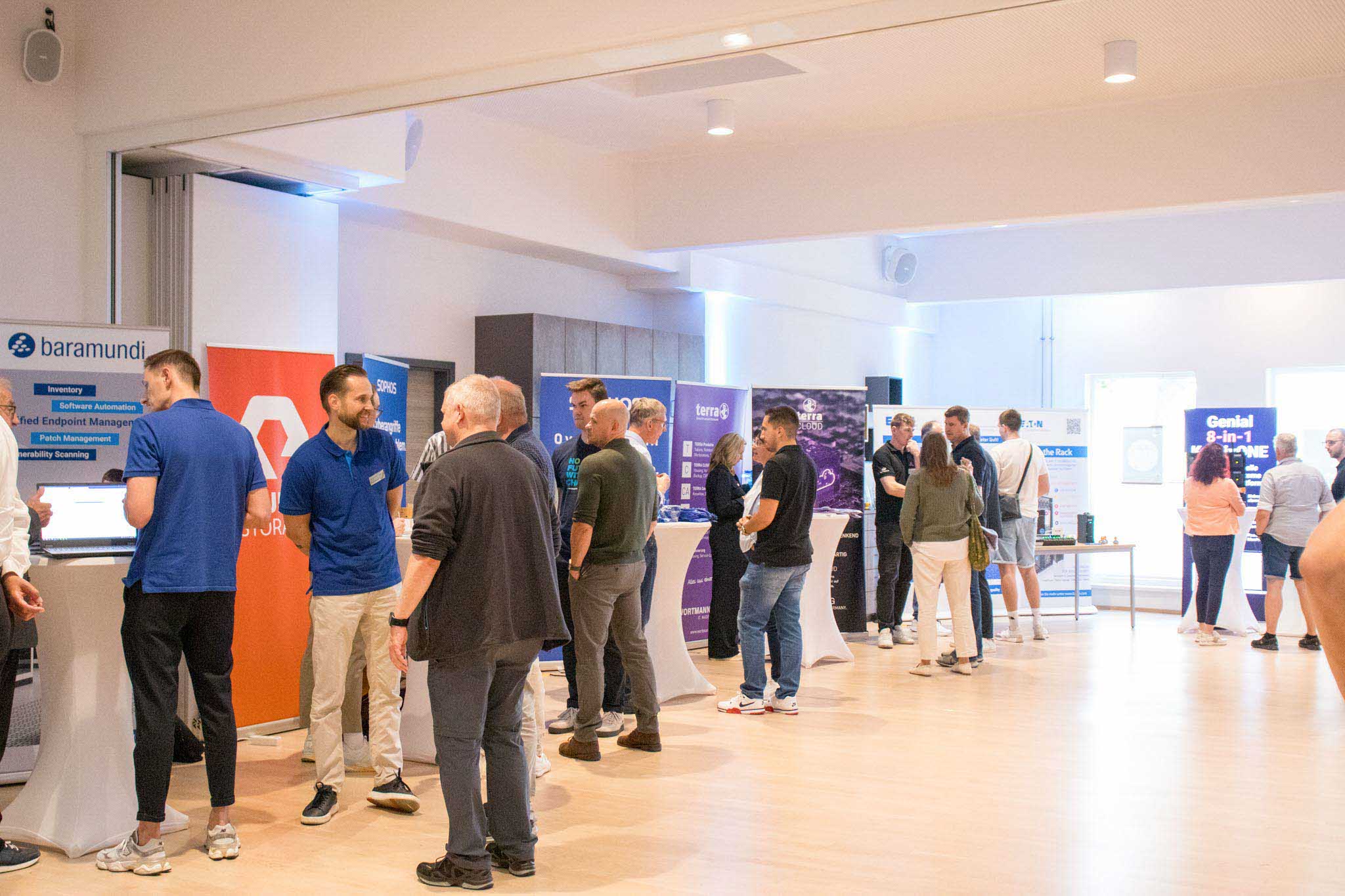 Besucher und Aussteller bei der IT-Messe des Kutzschbach Partnertags 2025 in einem hellen Raum mit Ständen von baramundi und weiteren Firmen
