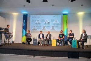 Podiumsdiskussion mit sechs Personen auf Bühne beim Kutzschbach Partnertag 2025, Hintergrund zeigt Präsentationsfolie mit Teilnehmernamen und Rollen